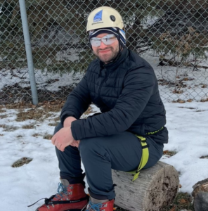 A picture of Ramy Penner in a navy blue ice climbing outfit and red boots with crampons.
